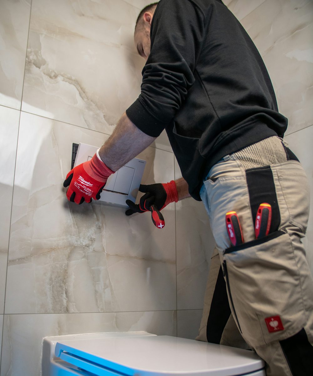 A plumber in work gloves fitting a new toilet