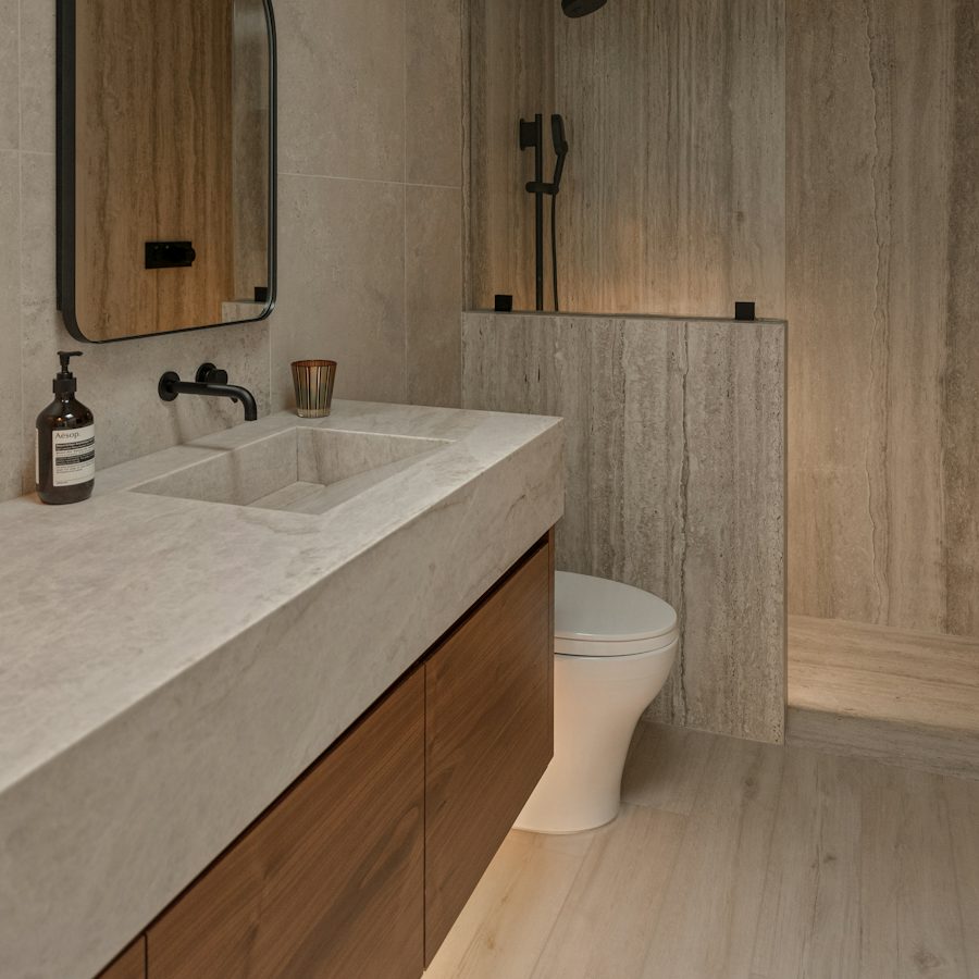 A finished bathroom with stone tiles and a wooden vanity
