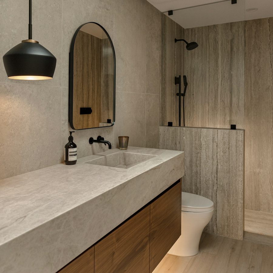 A wood vanity and stone tiles in a finished bathroom