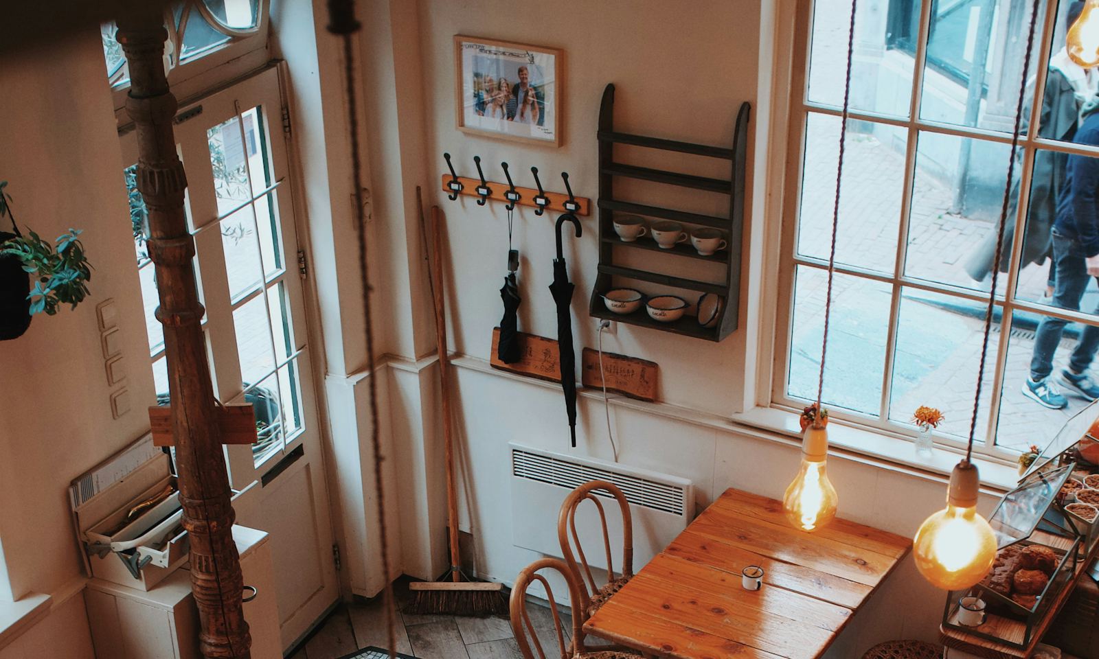 A cosy café with wooden tables, plants and warm lamps