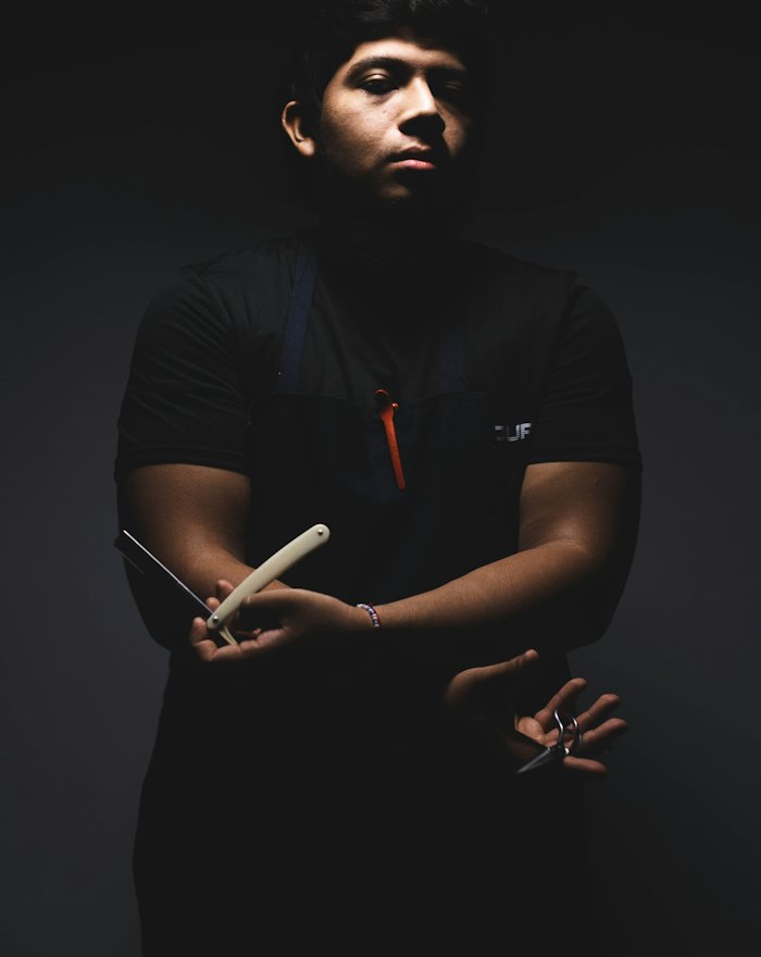Marcus with arms folded, holding a straight razor